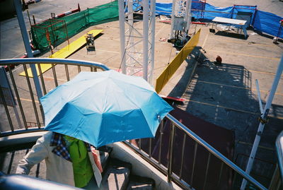 High angle view of person carrying umbrella while moving down on steps