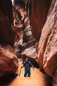 Man standing in stream amidst rock formation