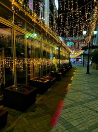 Illuminated street amidst buildings in city at night