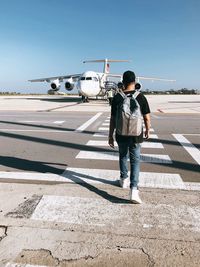 Full length rear view of man standing on airplane against sky
