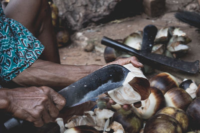 Midsection of man cutting coconuts