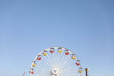 Low angle view of ferris wheel against clear blue sky