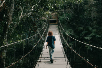 Rear view of man walking on footbridge