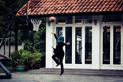 Side view of woman playing basketball in hijab