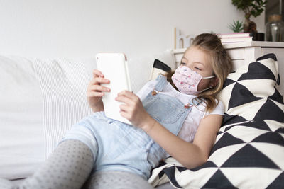 Girl using mobile phone on sofa at home