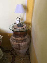 Close-up of lamp on table against wall at home