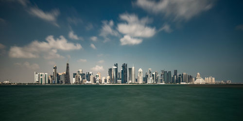 Sea by modern buildings against sky in city