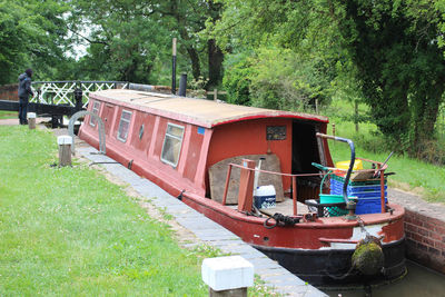 Abandoned boat moored on field by trees