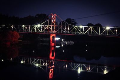 Illuminated suspension bridge against sky at night