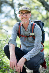 Portrait of backpacker kneeling on trail and smiling in california