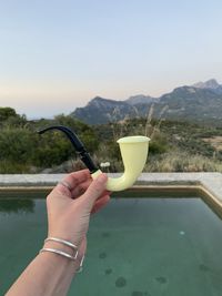 Midsection of person holding swimming pool against mountains