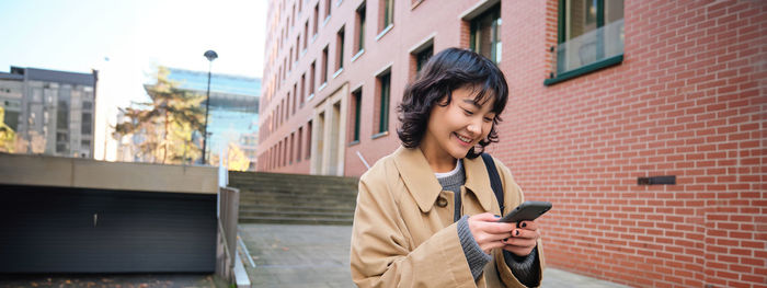 Side view of young man using mobile phone in city