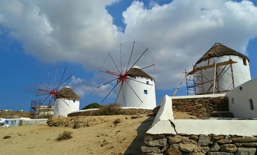 Traditional windmill by building against sky