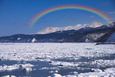 Scenic view of rainbow over mountains against sky