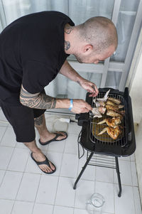 High angle view of man preparing meat on barbecue grill