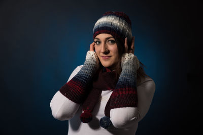 Portrait of young woman wearing warm clothing against blue background