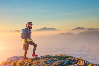 Side view of man standing on mountain against sky