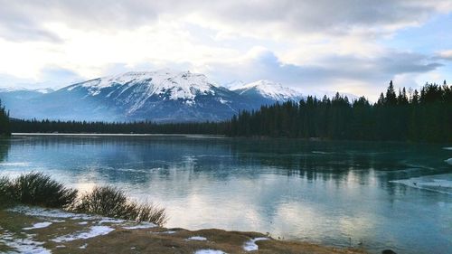 Scenic view of lake by snowcapped mountains against sky