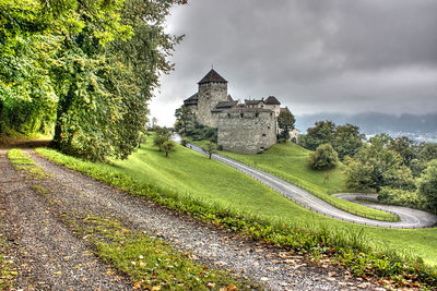 Castle on landscape against cloudy sky