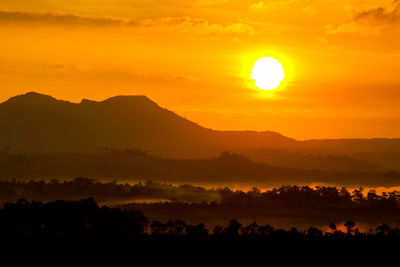Scenic view of silhouette mountains against orange sky