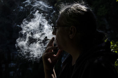 Man smoking cigarette against black background