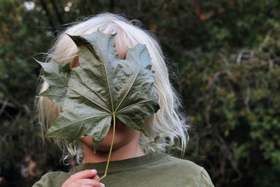 Girl hiding face with leaf