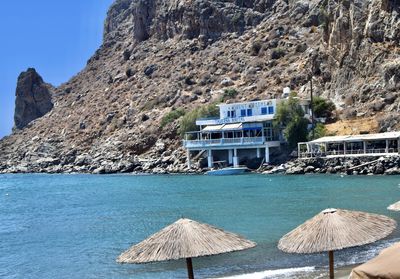 Deck chairs on rocks by sea against mountain