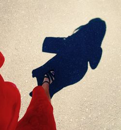 Low section of man with shadow on sand