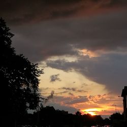 Low angle view of silhouette trees against dramatic sky