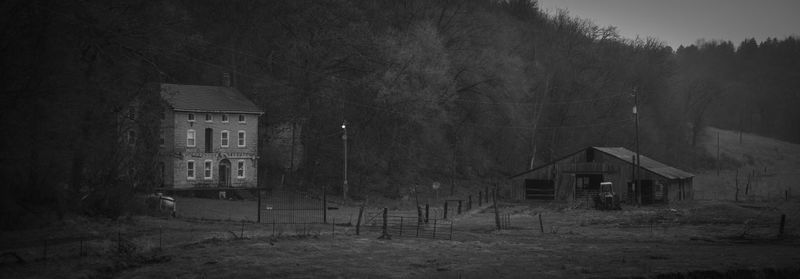 House on field by trees against sky