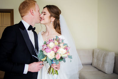 Portrait of bride holding bouquet kissing groom