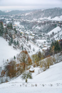 Aerial view of snowy townscape against hills and mountains during winter
