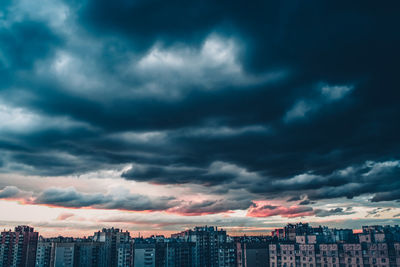 Buildings in city against dramatic sky