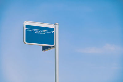 Low angle view of road sign against blue sky