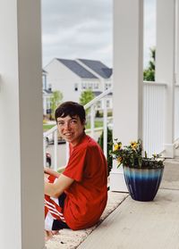 Portrait of smiling young woman sitting on sidewalk