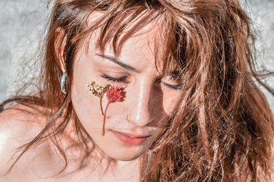 Close-up of woman with flowers on cheek