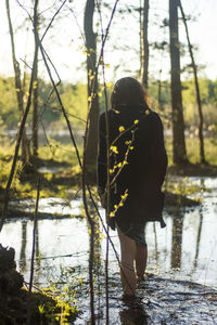 Rear view of woman walking in lake at forest