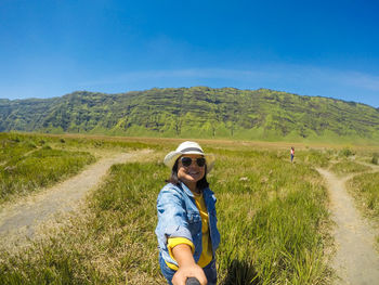 Woman wearing sunglasses standing against mountain during sunny day