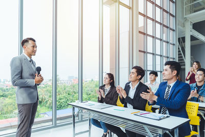 Businessman speaking on microphone with colleagues during seminar