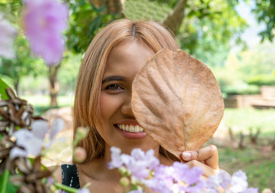Portrait of a smiling young woman holding leaf
