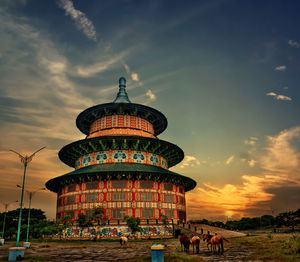 Group of people outside temple against sky during sunset