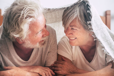 Smiling couple looking at each other while lying on bed