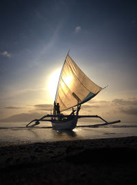 A fisherman standing on the boat with sunrise background.