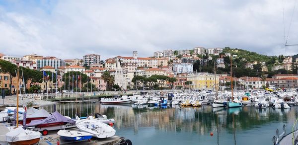 Boats moored in harbor against buildings in city