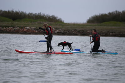 People paddleboarding with dog on river