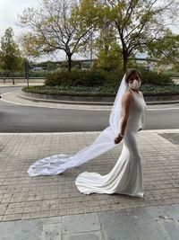 Full length of woman with umbrella on road against trees