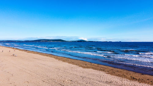 Scenic view of beach against clear blue sky