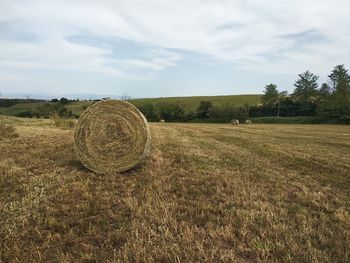 Hay bales on field against sky