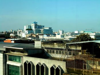 Buildings in city against clear blue sky