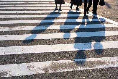 Shadow of people zebra crossing on street